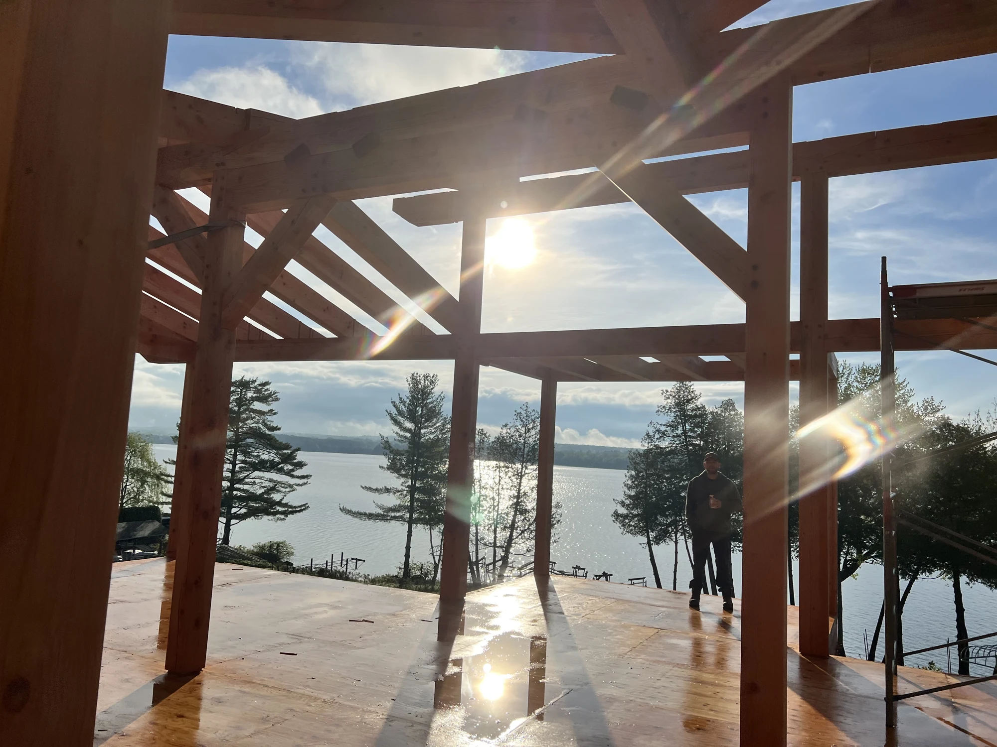 Soleil traversant la charpente en bois massif avec vue sur le lac