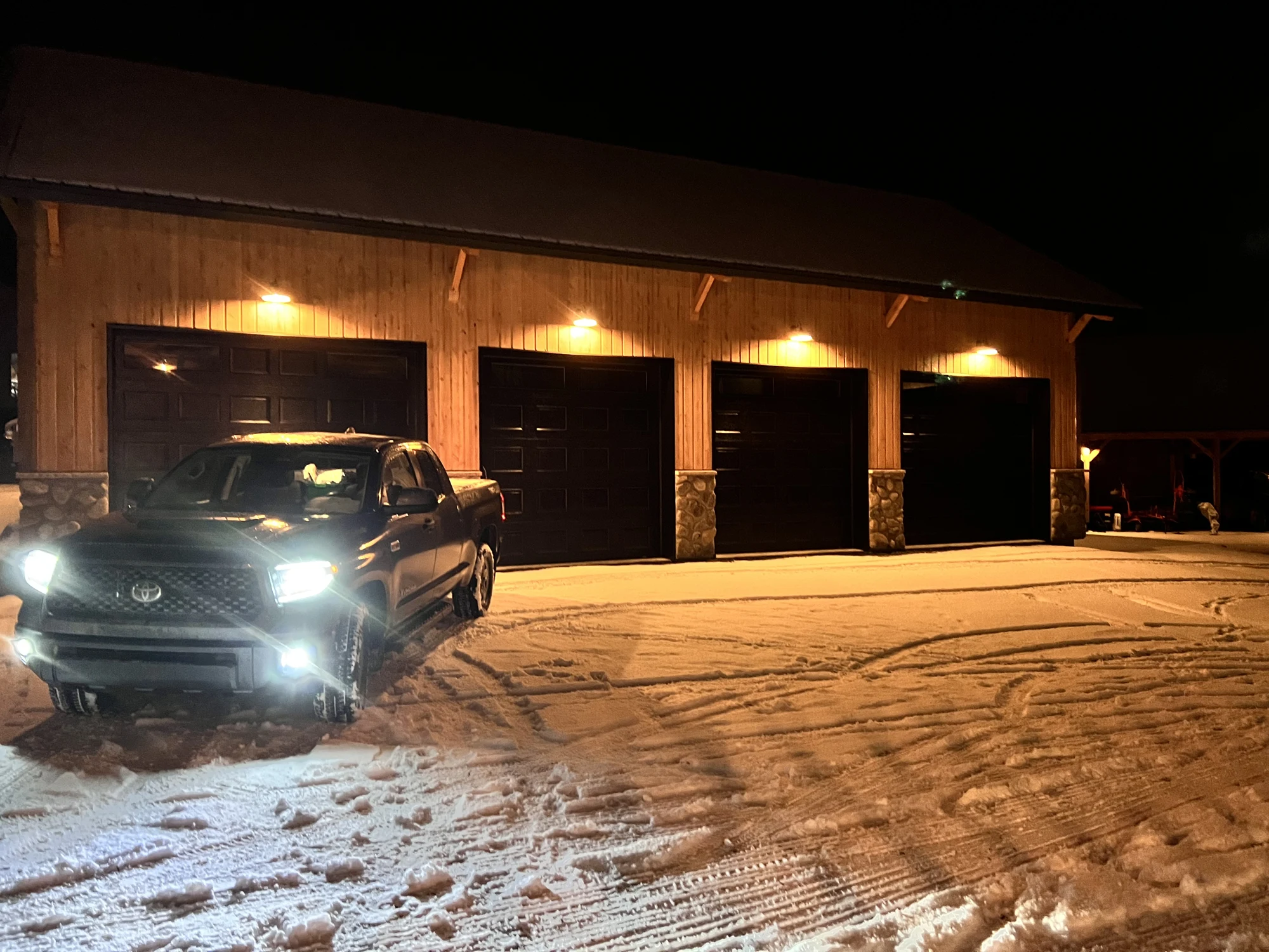 Garage terminé avec façade en bois et quatre portes éclairées de nuit