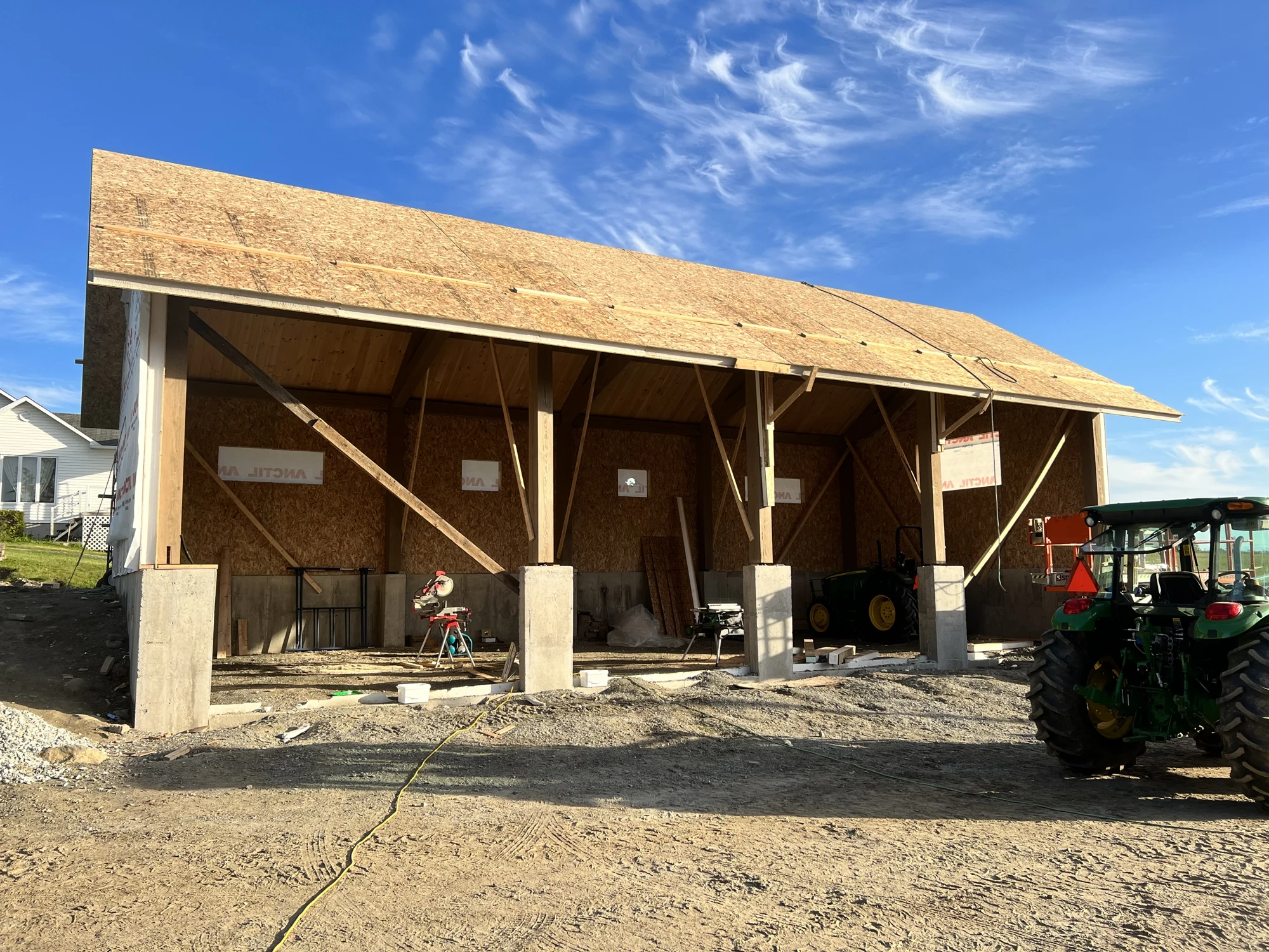 Garage en construction avec poteaux en bois massif et toiture en cours de fermeture
