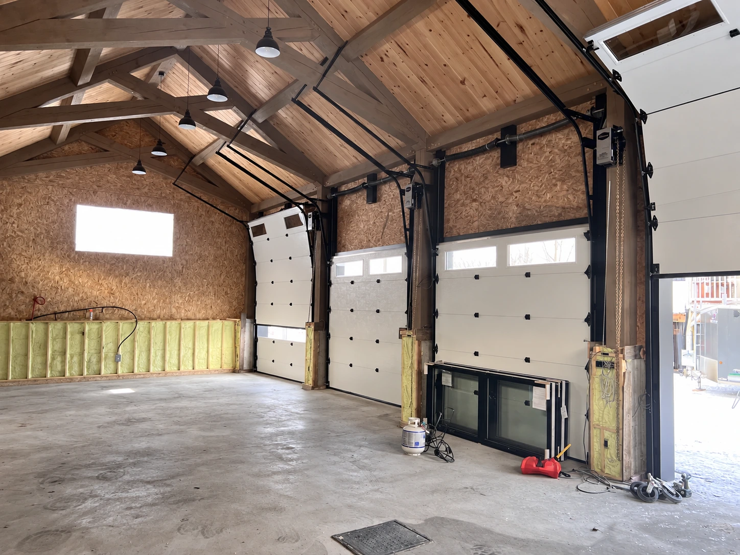Intérieur du garage avec charpente apparente et portes sectionnelles